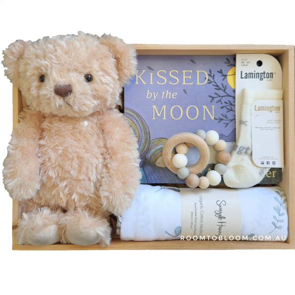 ROOM TO BLOOM Baci Baby Gift Hamper set with teddy bear, book, and other items in a wood box.