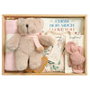ROOM TO BLOOM Blooming Beauty Baby Gift Hamper set in a light wood box featuring a plush teddy bear with a pink scarf, a folded pink swaddle, a floral baby outfit, a pink bow, and a book titled 'GUESS HOW MUCH I LOVE YOU'.