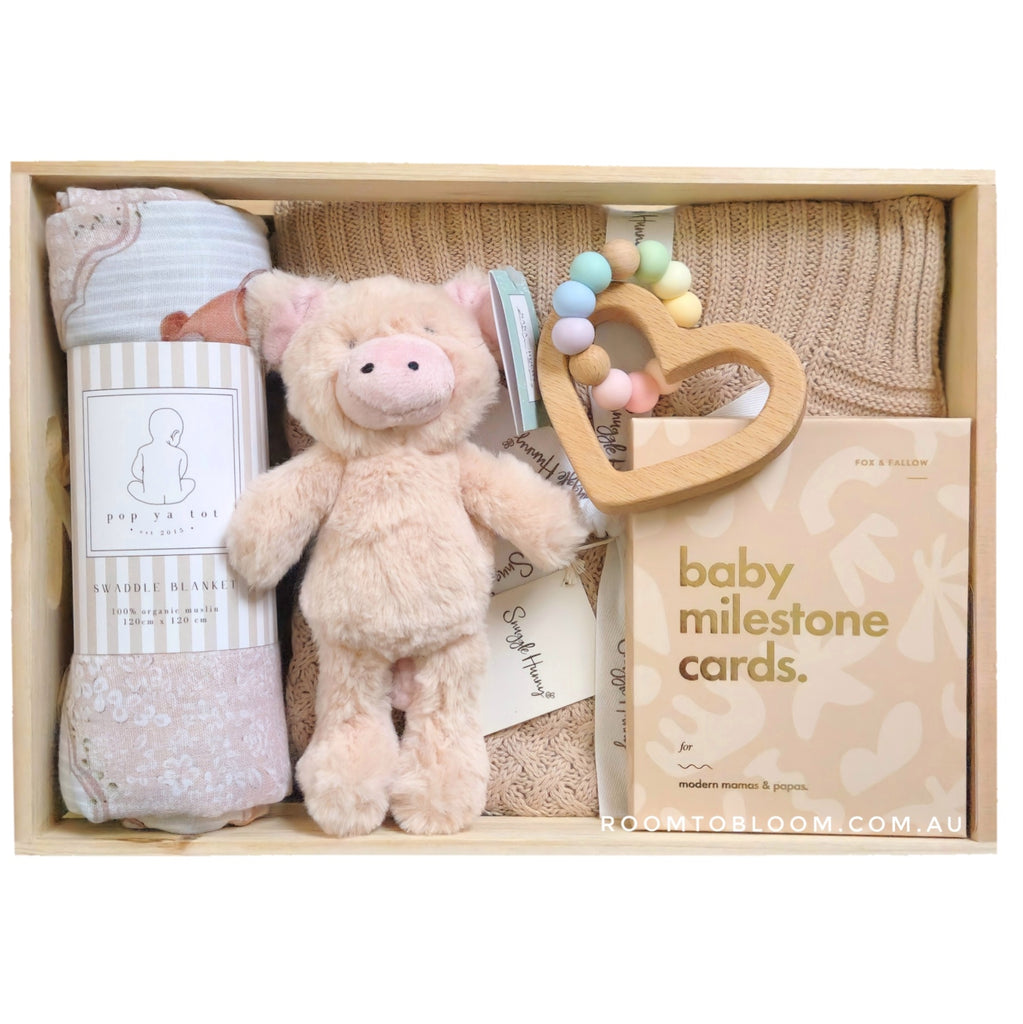 ROOM TO BLOOM Cinnamon Baby Gift Hamper set with plush toy, teether, milestone cards, and other items in a wooden box.