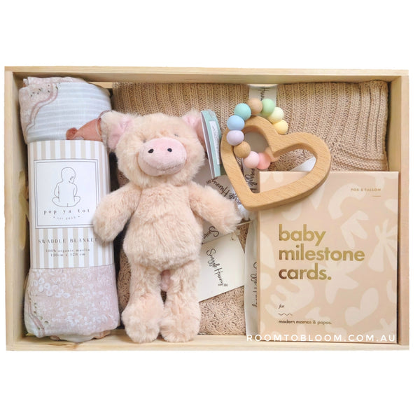 ROOM TO BLOOM Cinnamon Baby Gift Hamper set with plush toy, teether, milestone cards, and other items in a wooden box.