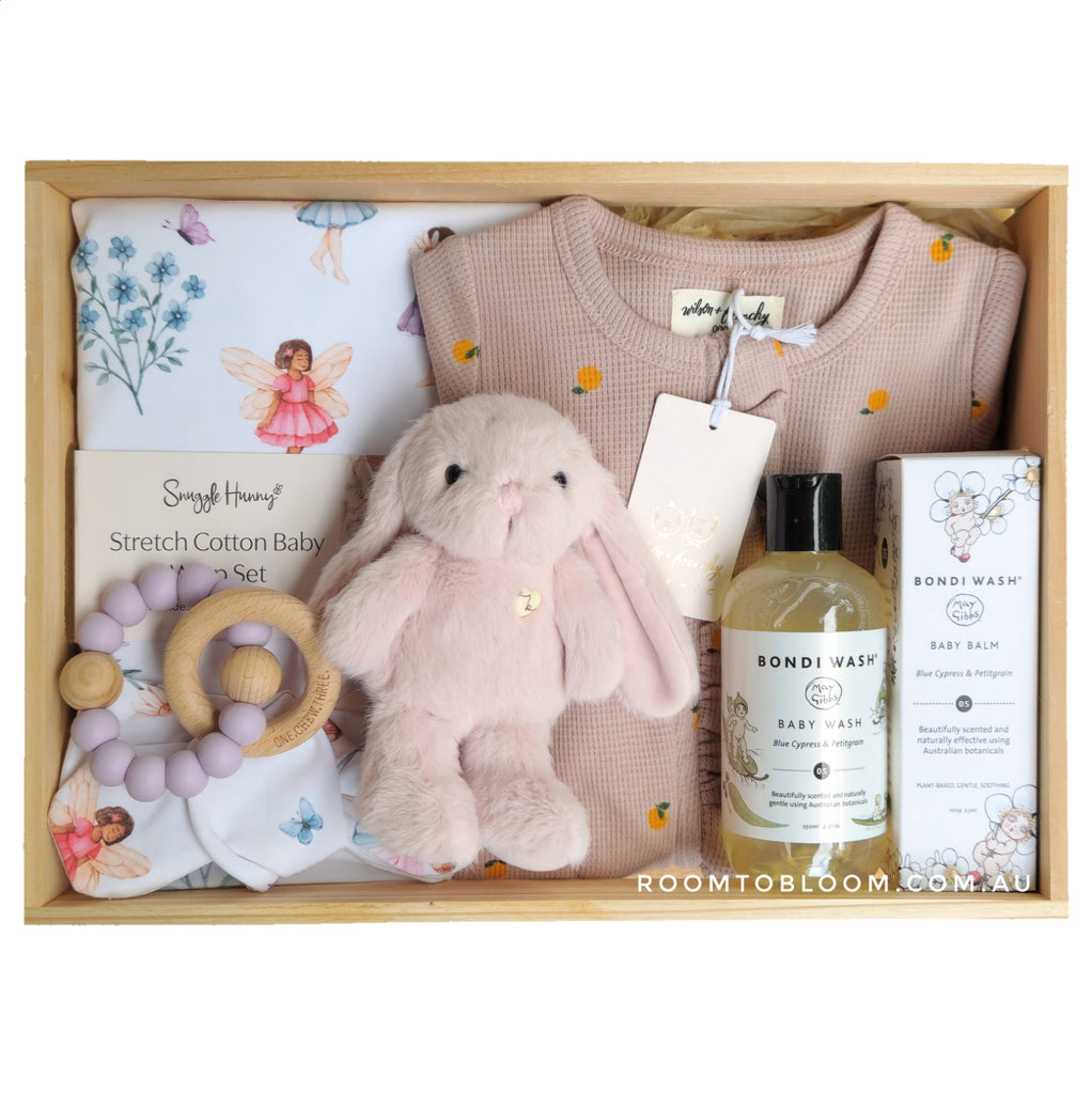 ROOM TO BLOOM Baby gift set with plush toy, clothing, skincare products and more in a wooden box.