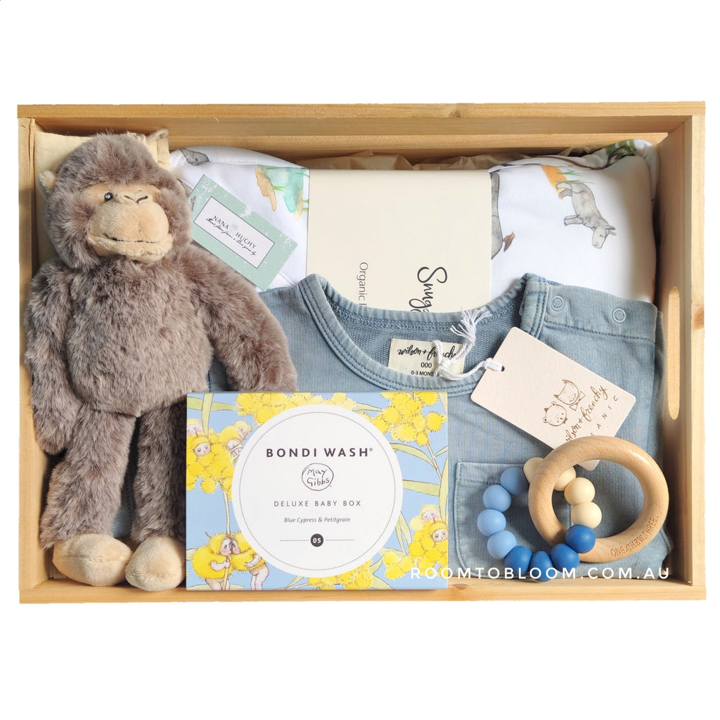 ROOM TO BLOOM Escapade Baby Gift Hamper set with plush toy, clothes, and baby bath products and more in a wooden box.