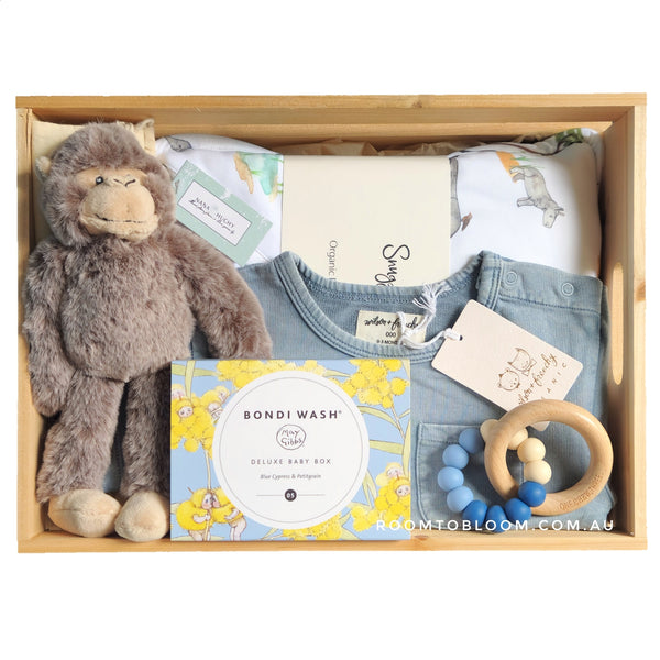 ROOM TO BLOOM Escapade Baby Gift Hamper set with plush toy, clothes, and baby bath products and more in a wooden box.