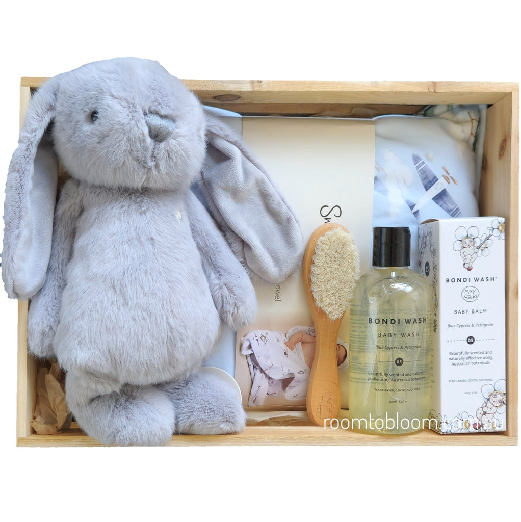 ROOM TO BLOOM Fly High Baby Gift Hamper set with plush toy, bath products, and a brush in a wooden box.