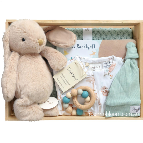 ROOM TO BLOOM Forest Friends Baby Gift Hamper set arranged in a light wood tray, featuring a plush beige bunny toy, a mint green baby hat, a wooden bead teether, a white baby romper with a printed pattern, a folded mint green blanket, and a book.
