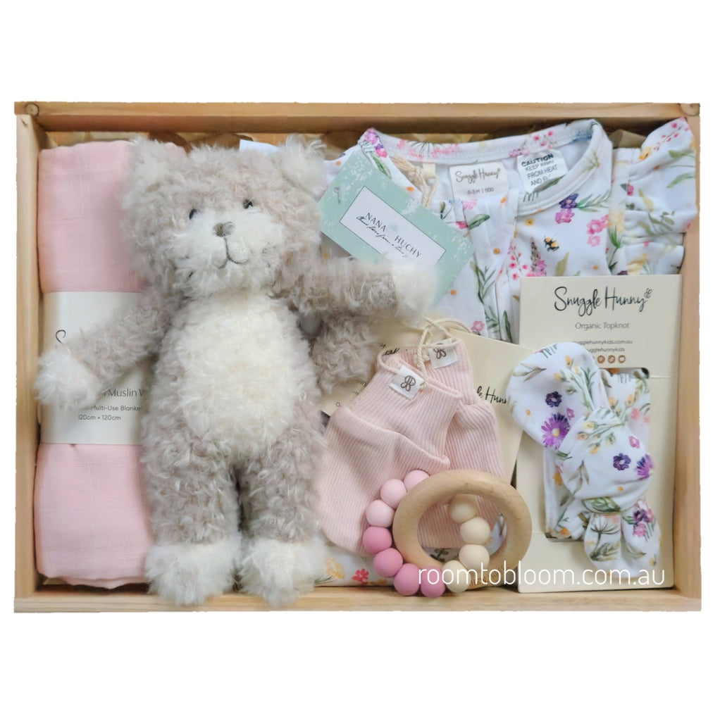 ROOM TO BLOOM Gracie Baby Gift Hamper set arranged in a wooden tray, featuring a plush kitten, folded pink swaddle, floral baby romper and headband, pink mittnes and a wooden bead teether.