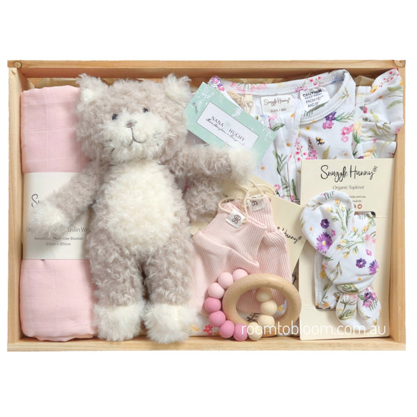 ROOM TO BLOOM Gracie Baby Gift Hamper set arranged in a wooden tray, featuring a plush kitten, folded pink swaddle, floral baby romper and headband, pink mittnes and a wooden bead teether.