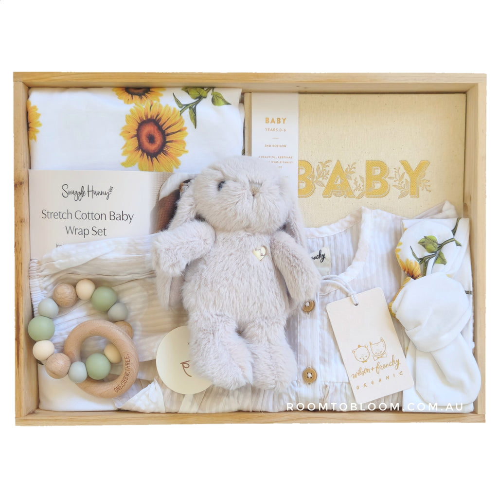 ROOM TO BLOOM Happy Days Baby Gift Hamper set with plush toy, wrap, and other items in a wooden box.