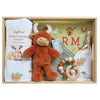 ROOM TO BLOOM Highlander Baby Gift Hamper set in a wooden box featuring a white stretch cotton baby wrap ad beanie set with farm illustrations, a plush brown bull toy, a green farm-themed book, a wooden bead rattle, and a sage bb.
