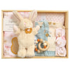 ROOM TO BLOOM Miss Daisy Baby Gift Hamper set in a wooden box featuring a cream plush bunny, a light blue denim baby romper, cream t-shirt, a pink knit blanket, a wooden bead teether, and a pink stretch baby wrap and headband. 