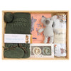ROOM TO BLOOM One Little Joey Baby Gift Hamper set arranged in a wooden tray, featuring an olive green knit bonnet and bootie set, a plush koala toy, a book titled 'This Little Joey', a cotton muslin cloth, and pacifiers.