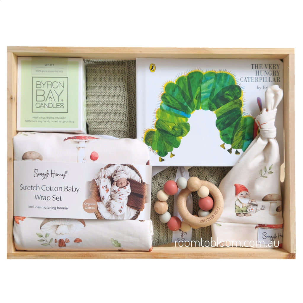 ROOM TO BLOOM Baby gift set with items including a baby wrap, candle, book, rattle and more in a wooden box.