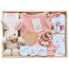 ROOM TO BLOOM Spring Posy Baby Gift Hamper set arranged in a light wood box, featuring a pink knit baby playsuit, a plush cream bunny toy, floral-patterned baby swaddle and headband, a wooden bead teether, and a Byron Bay candle.