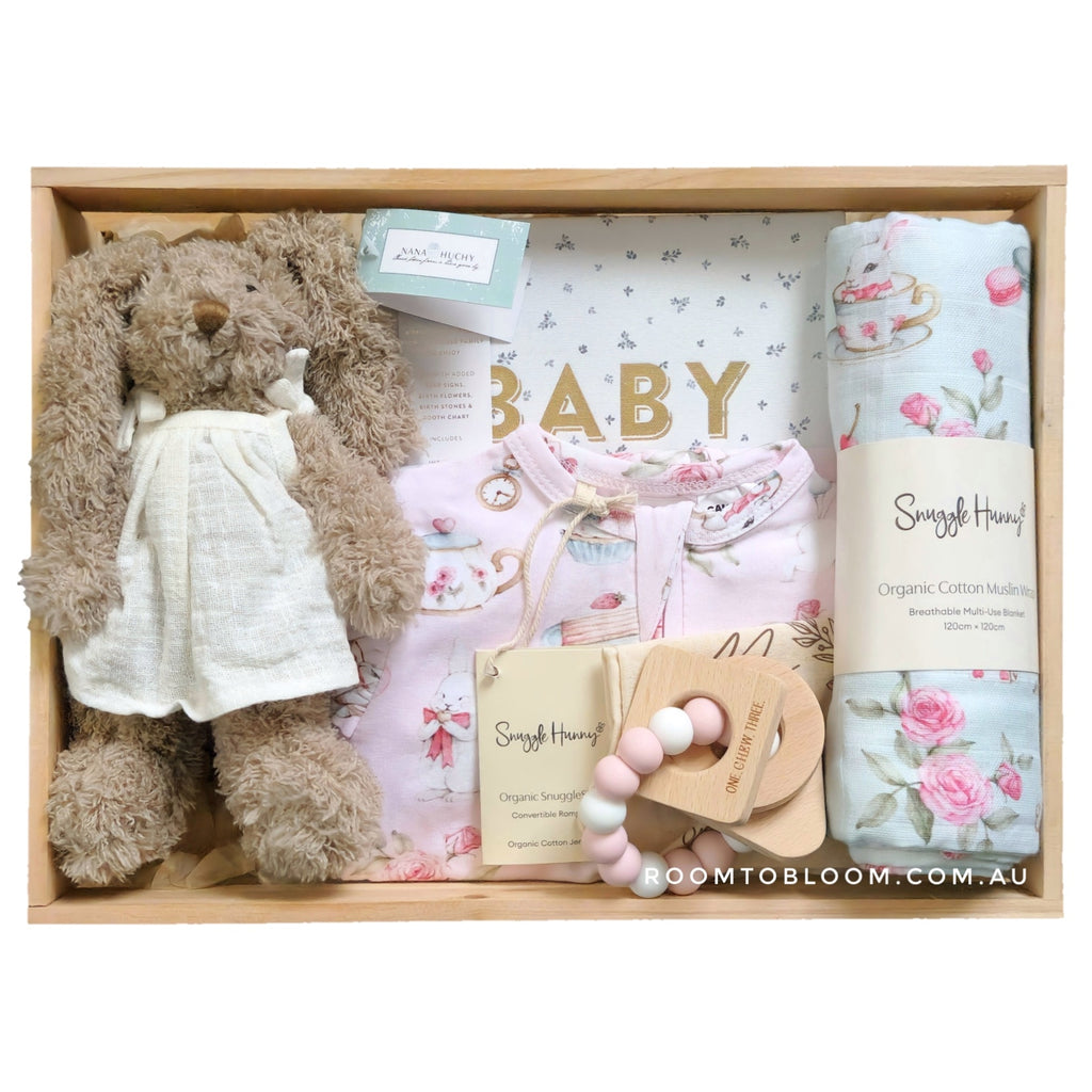 ROOM TO BLOOM Tea Party Baby Gift Hamper set with a toy bunny, swaddle, and other items in a wooden box.