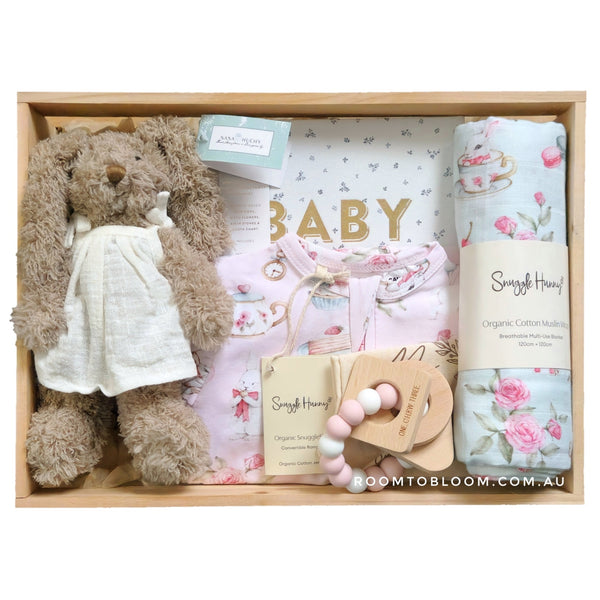 ROOM TO BLOOM Tea Party Baby Gift Hamper set with a toy bunny, swaddle, and other items in a wooden box.