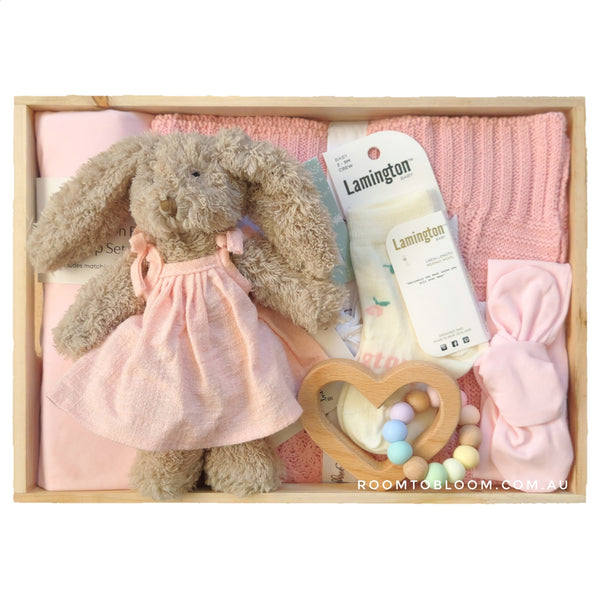 ROOM TO BLOOM Tickled Pink Baby Gift Hamper gift set with plush toy, blanket, and other items in a wooden box.