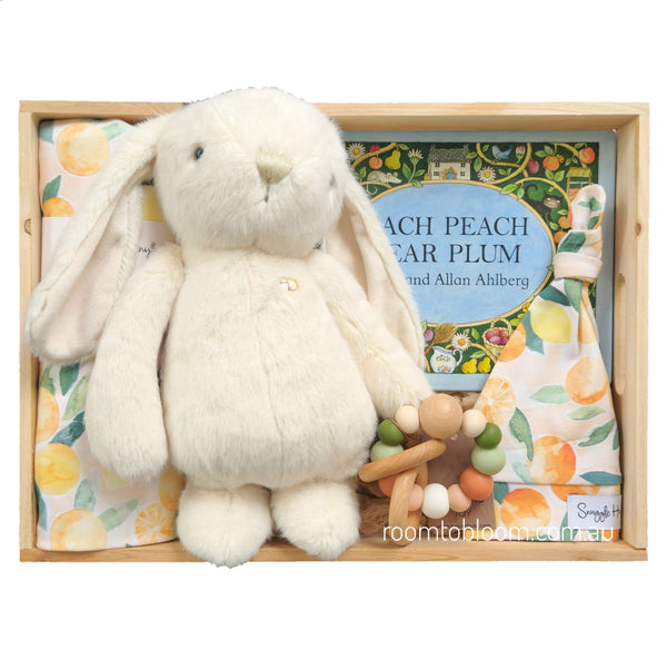 ROOM TO BLOOM Tutti Frutti Baby Gift Hamper box containing a plush cream bunny toy, a children's book titled 'Each Peach Pear Plum' by Allan Ahlberg, a peach-patterned wrap and beanie, and a wooden bead teether.