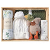 ROOM TO BLOOM Waddle and Toddle Baby Gift Hamper set in a light wood box containing a white cable-knit baby hat with a pom-pom, a rolled white cotton muslin wrap with green leaf print, an olive green knitted blanket, a plush duck toy, and Bondi Wash baby balm