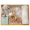 ROOM TO BLOOM Welcome Home Baby Gift Hamper set arranged in a wooden tray, featuring a plush bunny toy, a grey knit blanket, a patterned swaddle, a teething toy, a Byron Bay candles, and a beanie.
