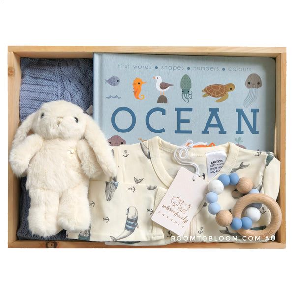 ROOM TO BLOOM Winter Whales Baby Gift Hamper set with plush toy, baby clothes, and more in a wooden box.