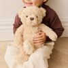 Child holding a SNUGGLE BUNNIES Arthur the Bear in a cozy indoor setting