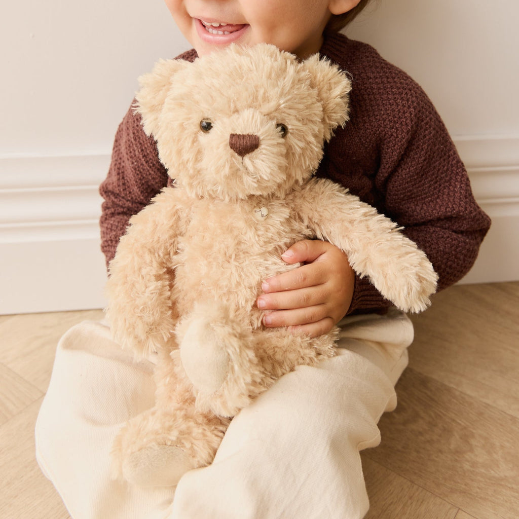 Child holding a SNUGGLE BUNNIES Arthur the Bear in a cozy indoor setting