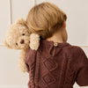 Child wearing a brown knitted sweater holding a SNUGGLE BUNNIES Arthur the Bear against a light-colored wall.