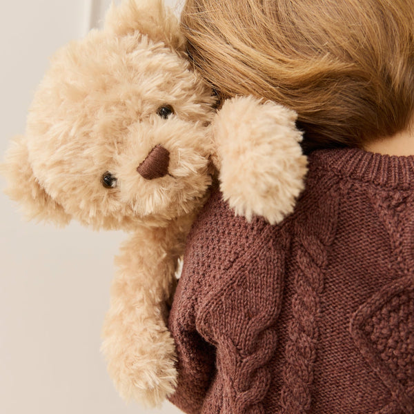 Person wearing a brown sweater holding a beige SNUGGLE BUNNIES Arthur the Bear against a neutral background