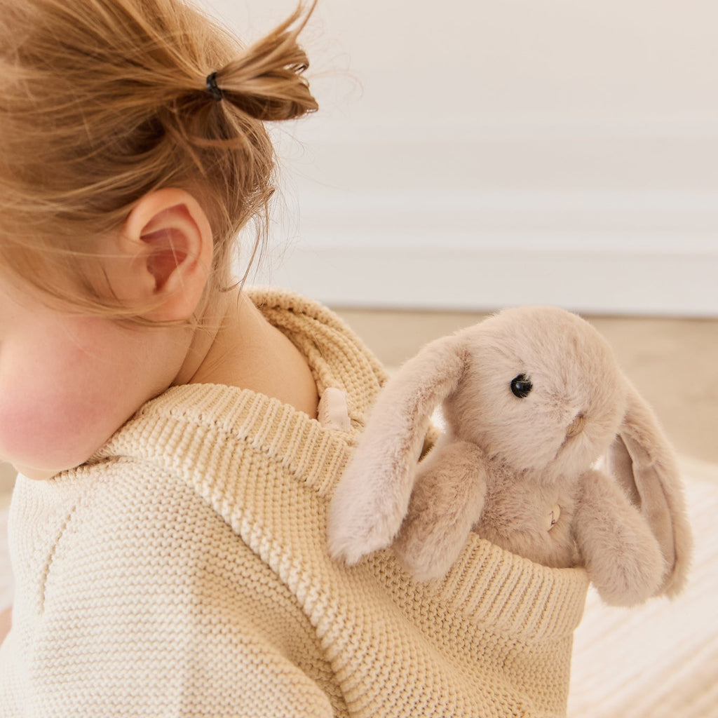 Child wearing a beige knit sweater with a plush SNUGGLE BUNNIES Little Penelope - Beige toy on a neutral background