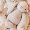 Child holding a SNUGGLE BUNNIES Penelope - Beige toy with floral patterns on clothing and background