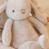 Plush SNUGGLE BUNNIES Penelope - Beige toy on a soft, patterned fabric background