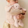 Young girl holding a pink plush SNUGGLE BUNNIES Penelope Bunny - Blossom toy against a plain background