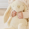 Child holding a plush SNUGGLE BUNNIES Penelope Bunny - Sunshine toy in a cozy setting