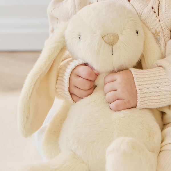 Child holding a plush SNUGGLE BUNNIES Penelope Bunny - Sunshine toy in a cozy setting