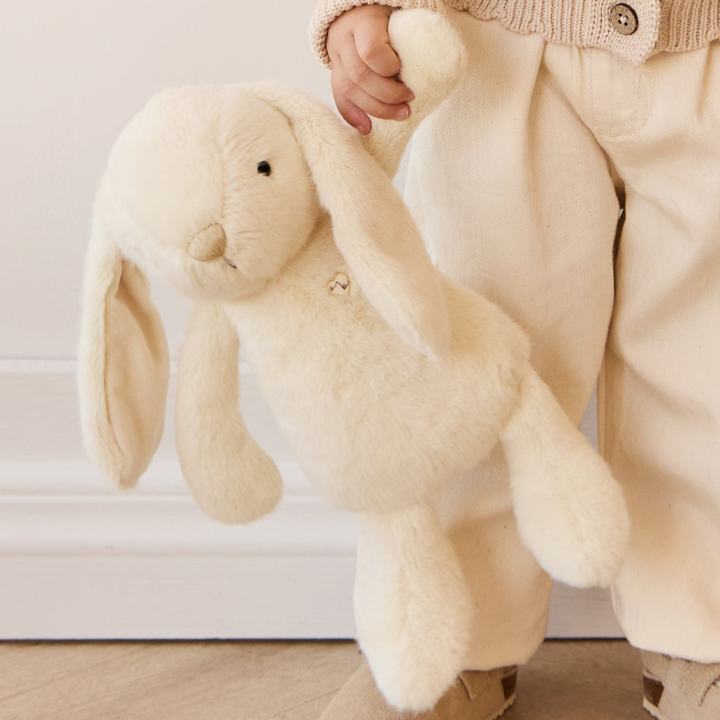 Child holding a plush SNUGGLE BUNNIES Penelope Bunny - Sunshine toy indoors