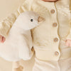 Baby in a cream-colored outfit holding a plush SNUGGLE BUNNIES Rose the Duck toy against a beige background