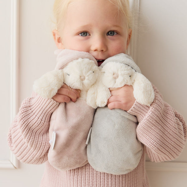 Child holding two SNUGGLE BUNNIES against a neutral background