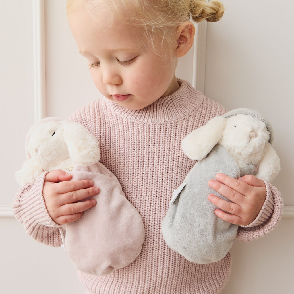 Child holding two SNUGGLE BUNNIES against a light background