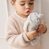 Child holding a SNUGGLE BUNNIES Sleeping Penelope - Blush toy against a light background