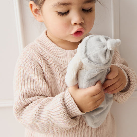 Child holding a SNUGGLE BUNNIES Sleeping Penelope - Blush toy against a light background