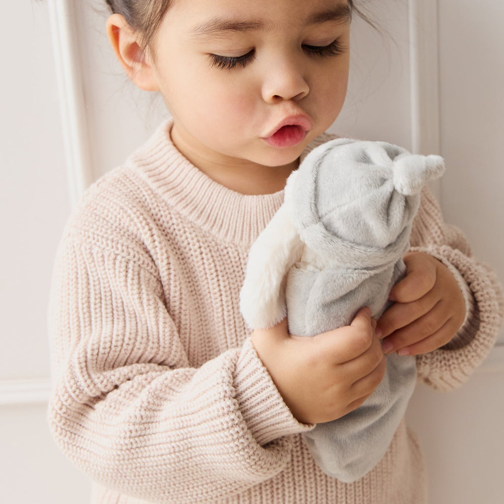 Child holding a SNUGGLE BUNNIES Sleeping Penelope toy against a neutral background